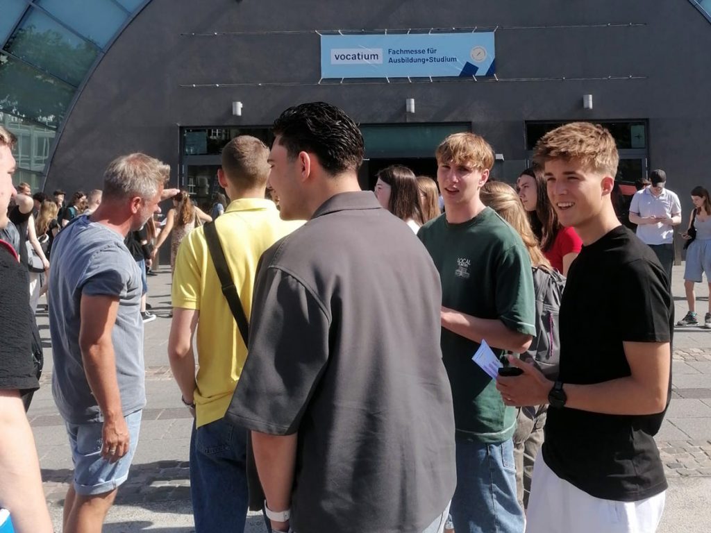 Schüler der Gesamtschule Rödinghausen stehen vor dem Eingang der Vocatium-Fachmesse für Ausbildung und Studium in Bielefeld. Nach den Gesprächen mit Unternehmen tauschen sie sich über ihre Eindrücke aus.