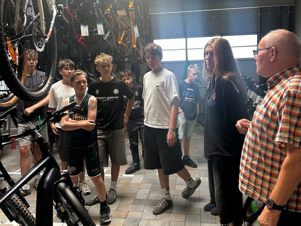 Mitglieder der Mountainbike-AG der Gesamtschule Rödinghausen erhalten im Fahrradfachgeschäft Fahrrad Schwan eine Führung durch die Werkstatt. Mitarbeitende erklären den Jugendlichen den Aufbau, die Wartung und die Reparatur moderner Fahrräder.