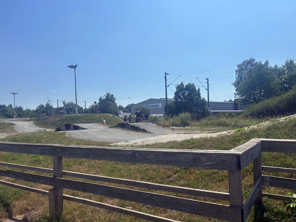 Schüler:innen der Mountainbike-AG fahren auf einem Pumptrack mit Wellen und Kurven. Auf der Strecke trainieren sie ihre Fahrtechnik und ihr Gleichgewicht.
