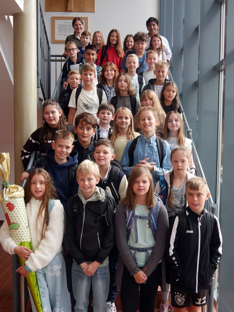 Die Schüler:innen der Klasse 5d stehen nach ihrer Einschulungsfeier gemeinsam mit ihrer Klassenleitung auf einer Treppe in der Gesamtschule Rödinghausen.